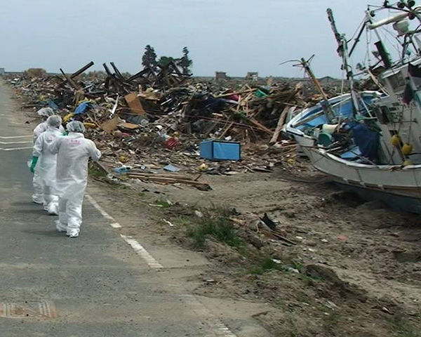 Workers walk down a road amid the debris after the tsunami